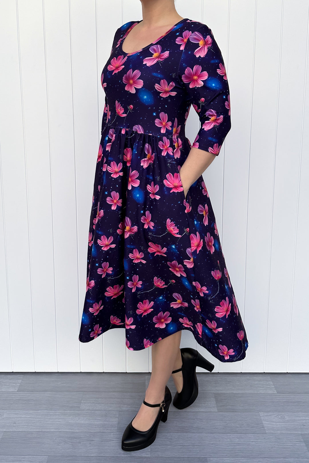 Woman wearing a floral dress with pink flowers on a navy galaxy background.