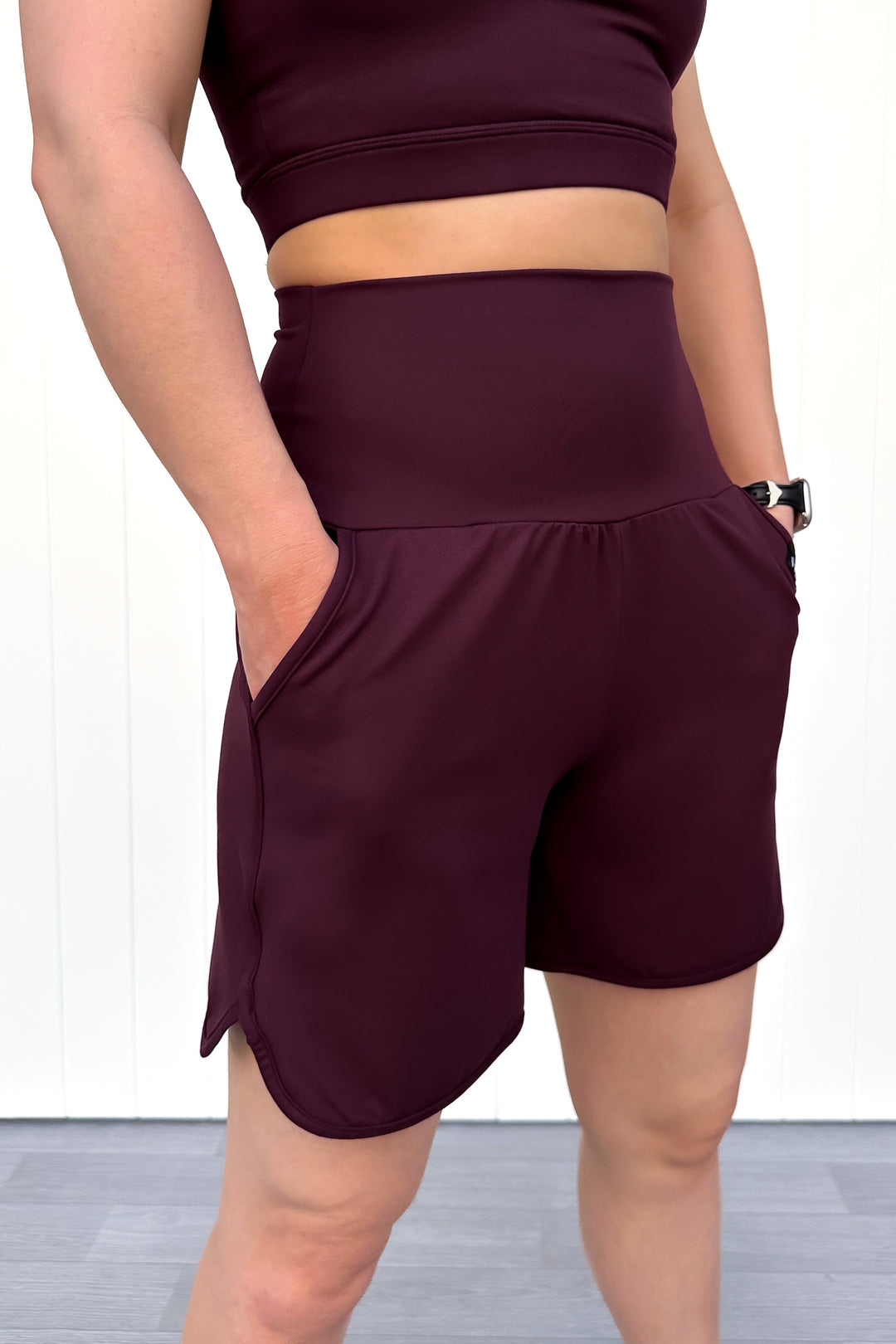 Person wearing maroon athletic shorts and top on a white background