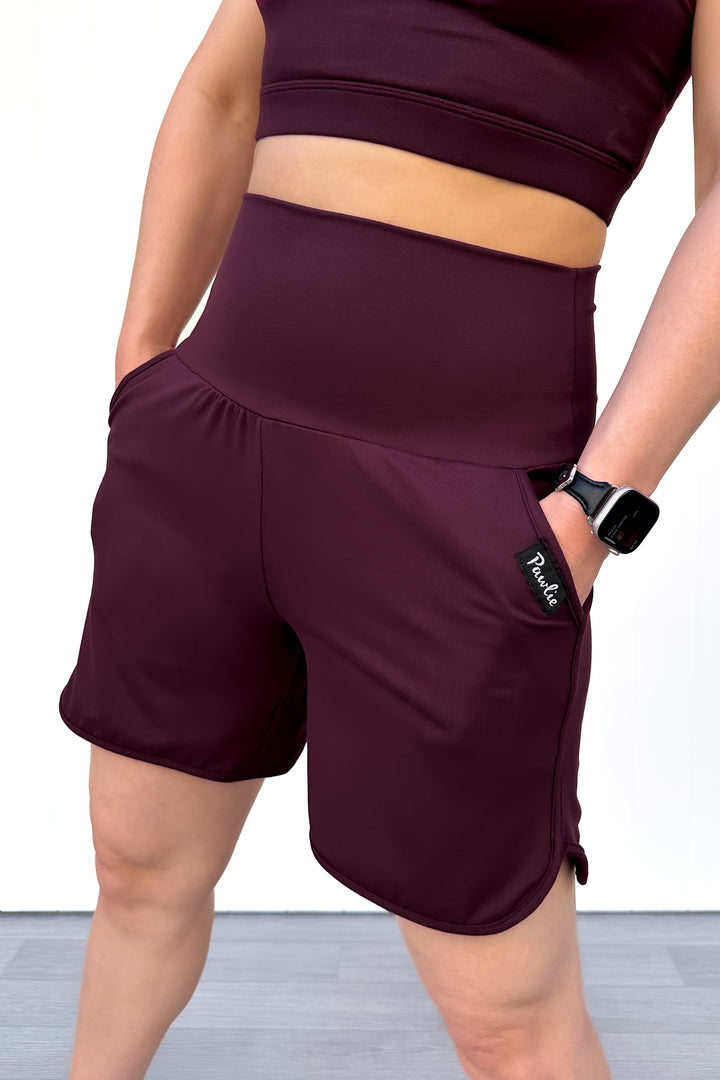 Person wearing maroon athletic shorts and top on a white background