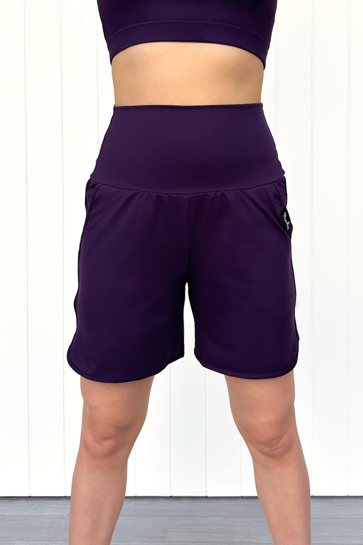 Purple athletic shorts worn by a person on a white background