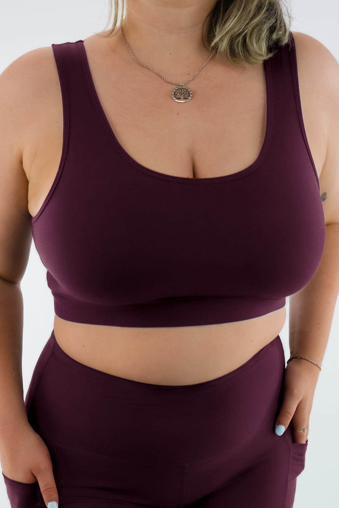 Person wearing a maroon sports bra and leggings set on a white background