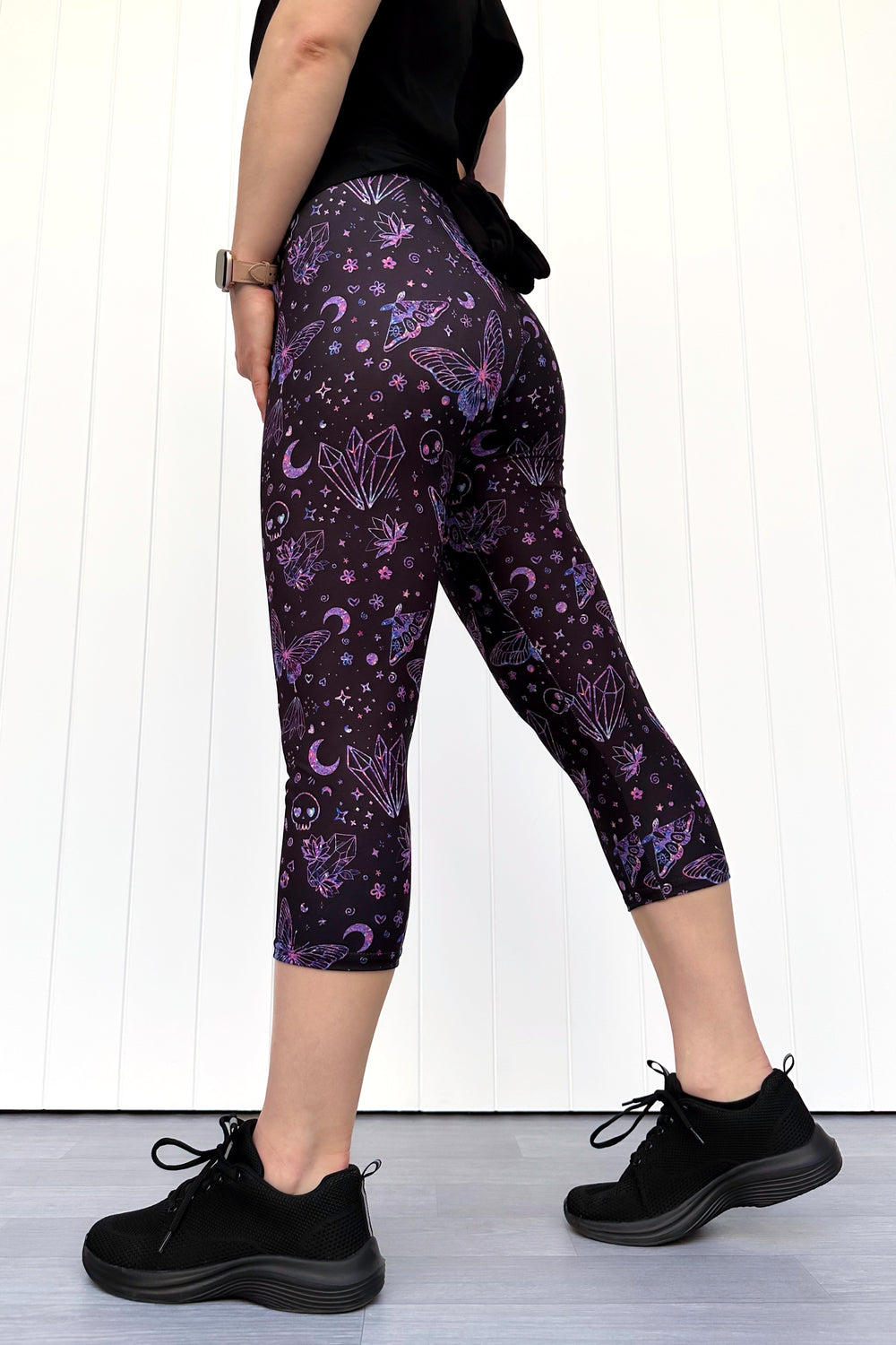 Person wearing purple capri leggings with celestial pattern on a white background