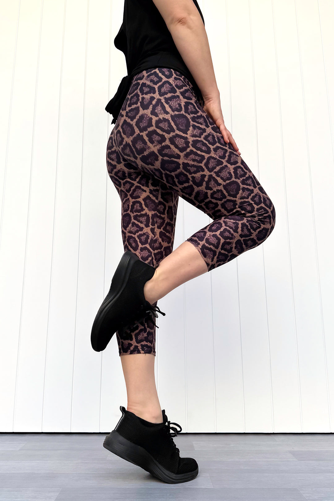 Person wearing leopard print leggings and black shoes on a white background