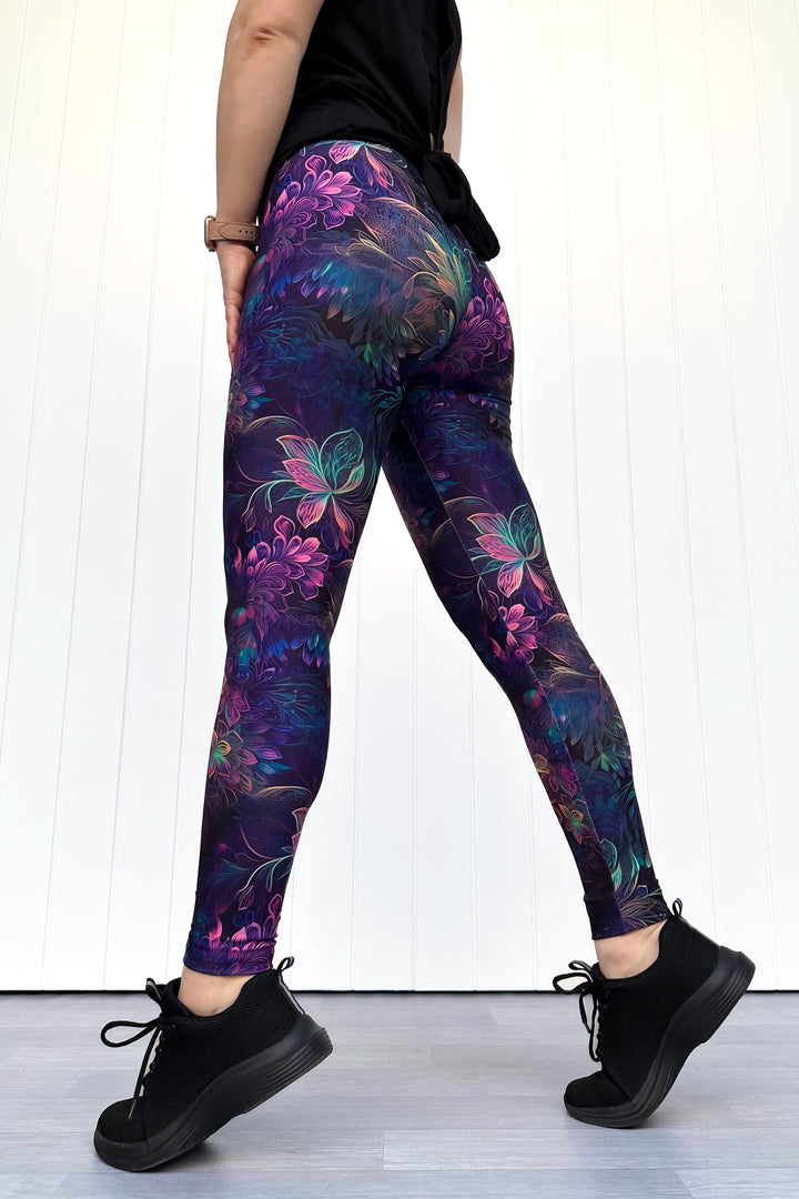 Person wearing purple floral leggings with a white background